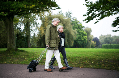 two elderly people walk with portable oxygen concentrator