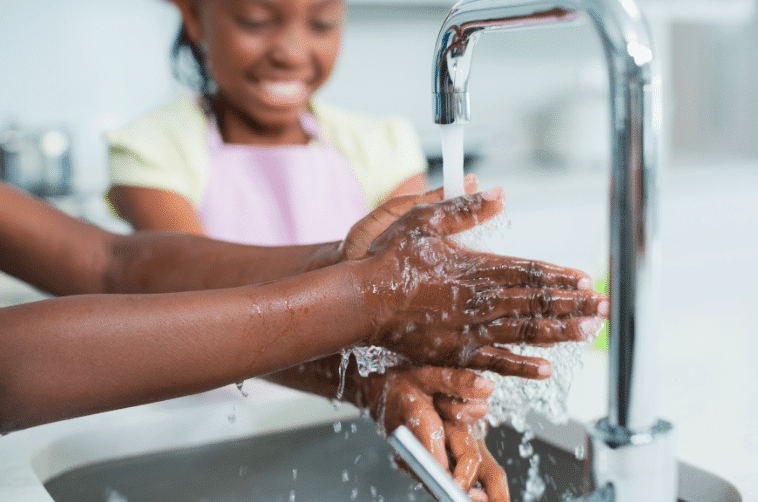 A child and parent washing their hands to prevent infection and disease.