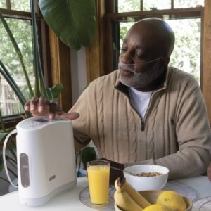 Man using Oxlife Liberty Portable Oxygen Concentrator sitting at his breakfast table