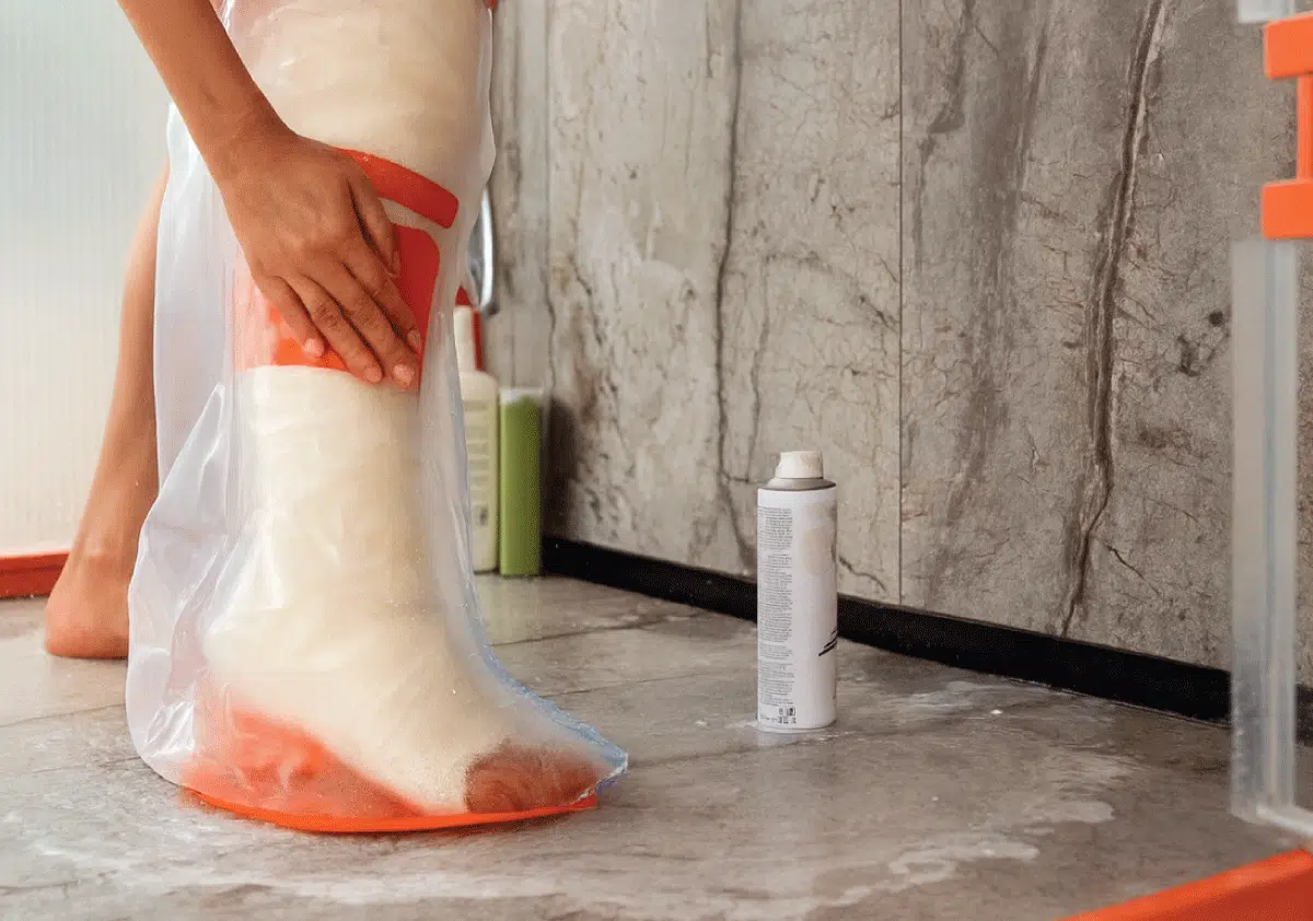 Person protecting a leg cast with a waterproof cover in the shower
