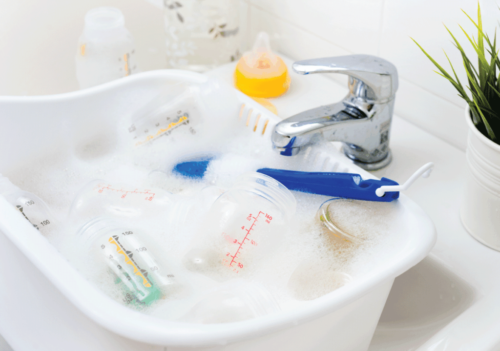 Breast pump parts and baby bottles being cleaned in soapy water