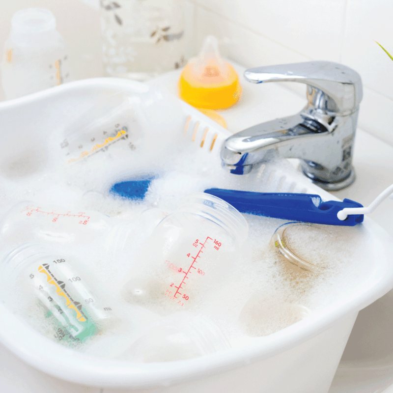 Breast pump parts and baby bottles being cleaned in soapy water