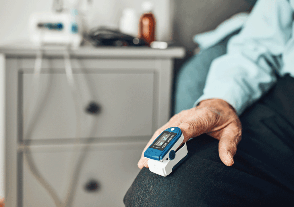 Senior patient measuring oxygen saturation with a fingertip pulse oximeter at home.