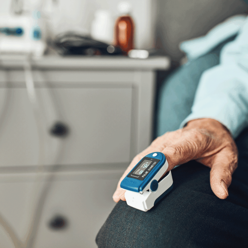 Senior patient measuring oxygen saturation with a fingertip pulse oximeter at home.