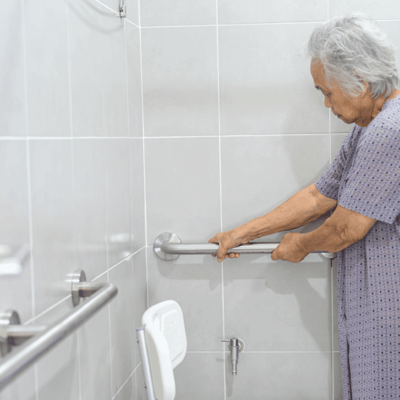 Senior woman using grab bars in bathroom for safe recovery after surgery at home