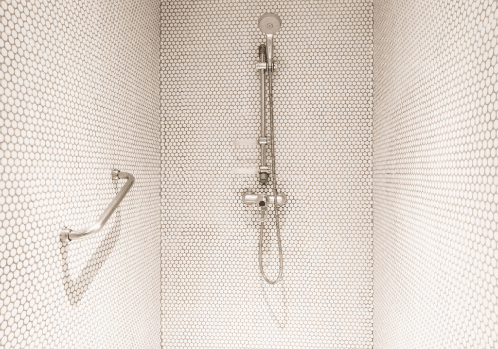 Accessible shower with grab bar and handheld showerhead for safe bathing in small bathrooms